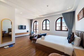 Una habitación de hotel moderna con una cama grande, un escritorio, una silla y un televisor.