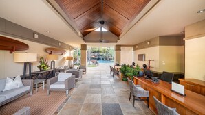 Un'ampia hall con soffitto in legno, una reception, comodi posti a sedere e vista su una piscina all'aperto.