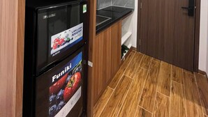 Une cuisine de taille réduite, avec des meubles de rangement en bois, un réfrigérateur noir et une porte en bois.