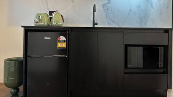 Una cocina moderna con un refrigerador negro, horno integrado y salpicadero de mármol.