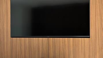 A modern room with a large flat-screen TV mounted on a wooden wall, a marble-topped table, and a bench.