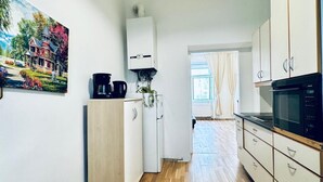 Eine moderne Küche mit Holzboden, weißen Schränken, einer schwarzen Mikrowelle und einer Deckenleuchte.