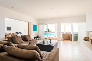 Una sala de estar moderna con un conjunto de sofás, una mesa de centro y vista a una piscina.