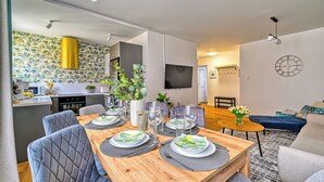A modern living space with a dining area, kitchen, and seating area. - Apartamenty Sun & Snow Pod Ratuszem (Jelenia Góra)