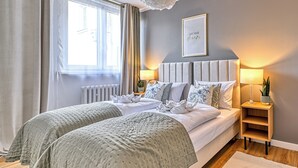 A double bed with a grey headboard, two bedside tables with lamps, a framed inspirational quote on the wall, and a window with curtains. - Apartamenty Sun & Snow Pod Ratuszem (Jelenia Góra)