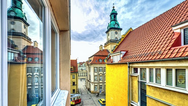 A street view with buildings, a tram, and a clear sky. - Apartamenty Sun & Snow Pod Ratuszem (Jelenia Góra)