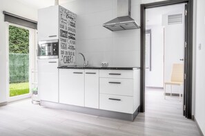 A modern kitchen with white cabinets, a stainless steel range hood, and a black countertop. - Rural Apartment Río Pas 3 (Oruña)