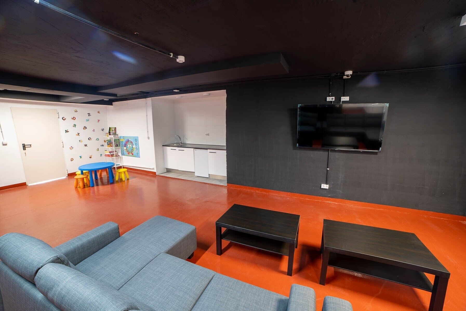 A modern living room with sofas, a TV, and a kitchen area.