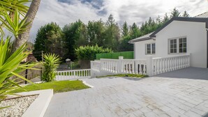 En vit byggnad med en asfalterad uppfart, ett vitt staket och ett grönt staket i bakgrunden.