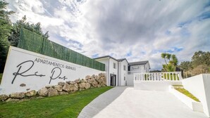 En modern byggnad med en stenmur och en skylt med texten ”APARTAMENTOS RURALES Rio Pas”.