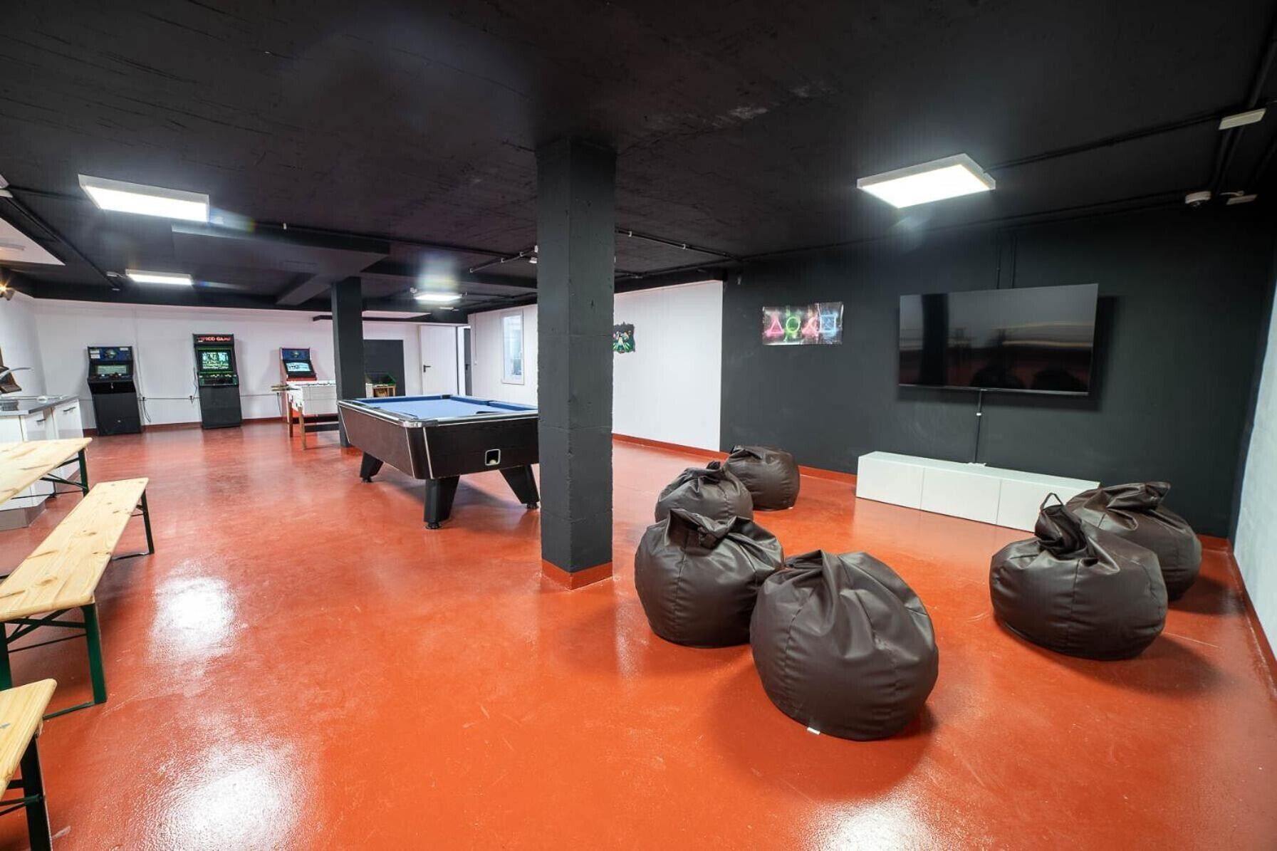 Una sala ricreativa con tavolo da biliardo, sacchi di fagioli e macchinette giochi.