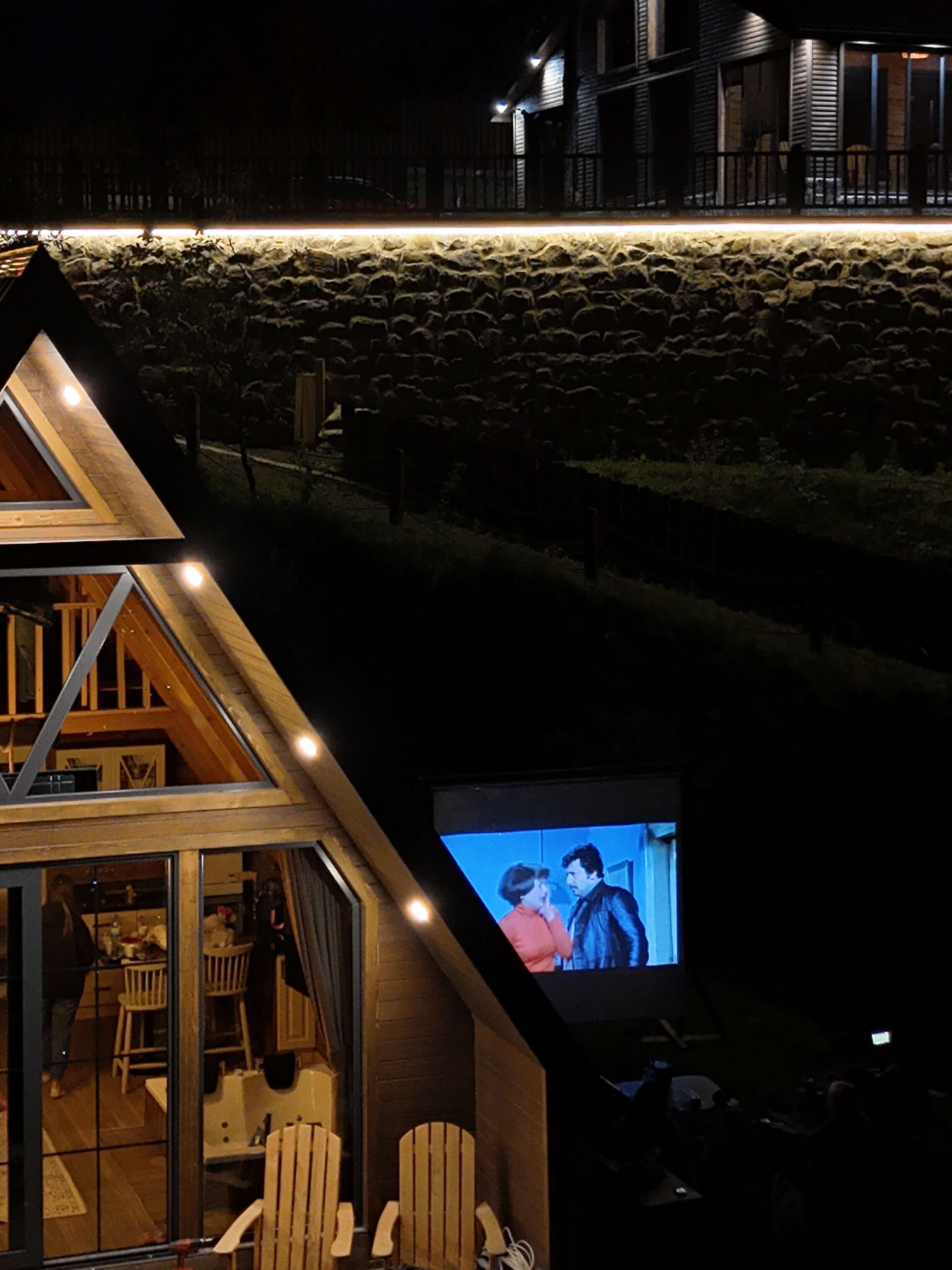A cozy cabin with a stone foundation, wooden interior, and a television screen displaying a movie.