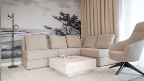 Ein modernes Wohnzimmer mit einem beigefarbenen Ecksofa, einem runden Couchtisch und einer schlichten Einrichtung.