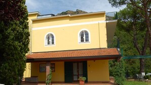 A two-story yellow building with a red-tiled roof, two arched windows, and a small porch area. - Villa Ninì Accommodation Salerno (Campania)