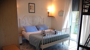 A bedroom with a white metal bed frame, blue bedding, a bedside table, and a patterned floor. - Villa Ninì Accommodation Salerno (Campania)