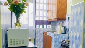 A compact kitchen with a refrigerator, stove, and wooden cabinets. - Naivasha Budget Suites  (Naivasha)