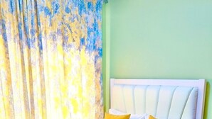 A bed with white bedding and a yellow accent, a white headboard, and a green wall. - Naivasha Budget Suites  (Naivasha)