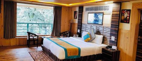 A wooden-floored bedroom with a bed, bedside table, and a window with curtains.