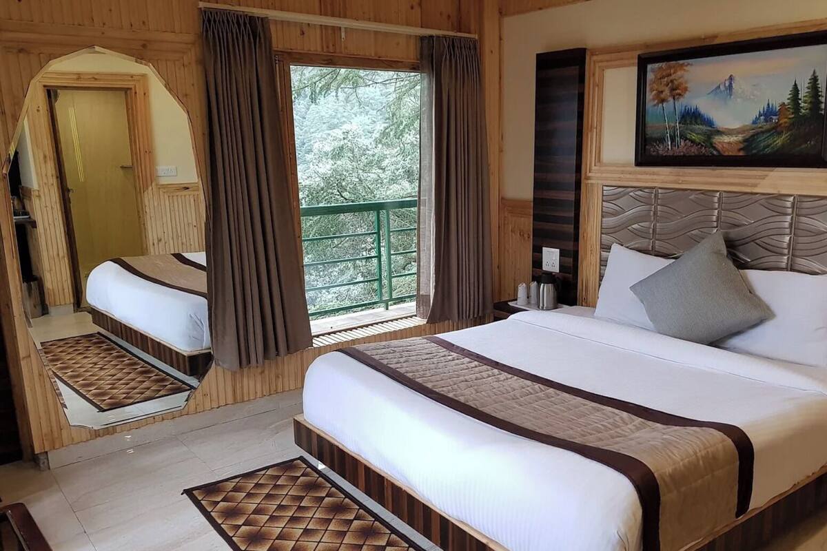 A bedroom with a large bed, a wooden headboard, a painting, a window with curtains, and a view of trees.