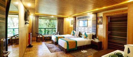 A wooden-floored bedroom with two beds, a dining table, and a balcony with curtains.