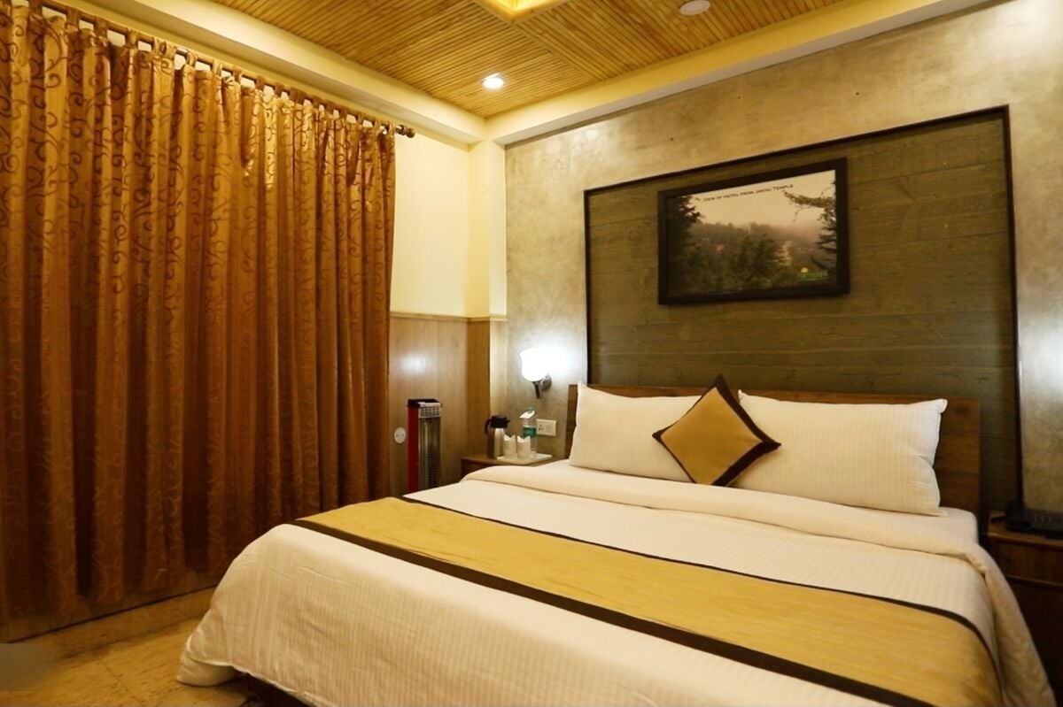 A hotel room with a large bed, wooden headboard, and a framed picture on the wall.