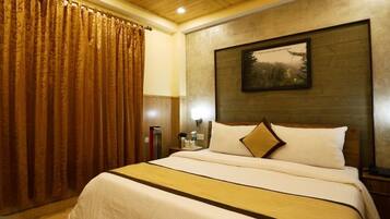 A hotel room with a large bed, wooden headboard, and a framed picture on the wall.