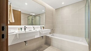 A modern bathroom with two sinks, a bathtub, and a glass shower enclosure. - 2BR plus M Pet-Friendly Prime Amenities (Dubai)