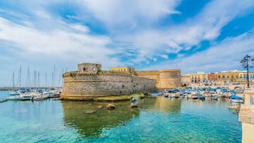 Un'antica fortezza con un fossato, circondata da una marina piena di imbarcazioni.