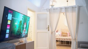 Una habitación con televisión mostrando Netflix, una cama con dosel y vistas a un balcón.