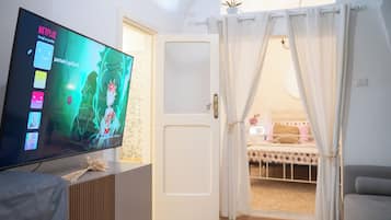 Una stanza con televisione che mostra Netflix, un letto a baldacchino e vista su un balcone.