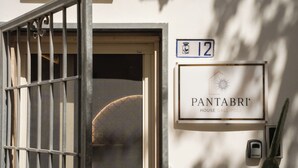 Entrada de un edificio con una verja metálica, una puerta y un cartel que indica 'PANTABRI HOUSE GALLIPOLI' con el número '12' arriba.