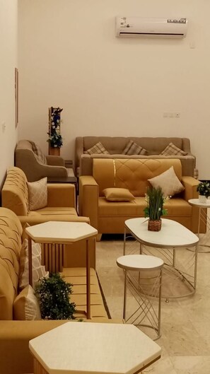 Un salon comprenant un canapé, deux fauteuils, une table basse et une table d’appoint.