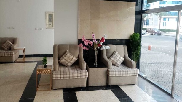 Un hall d’hôtel avec deux canapés, une petite table et un vase de fleurs.
