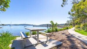 A picnic table by a lakeside path with boats in the background.
