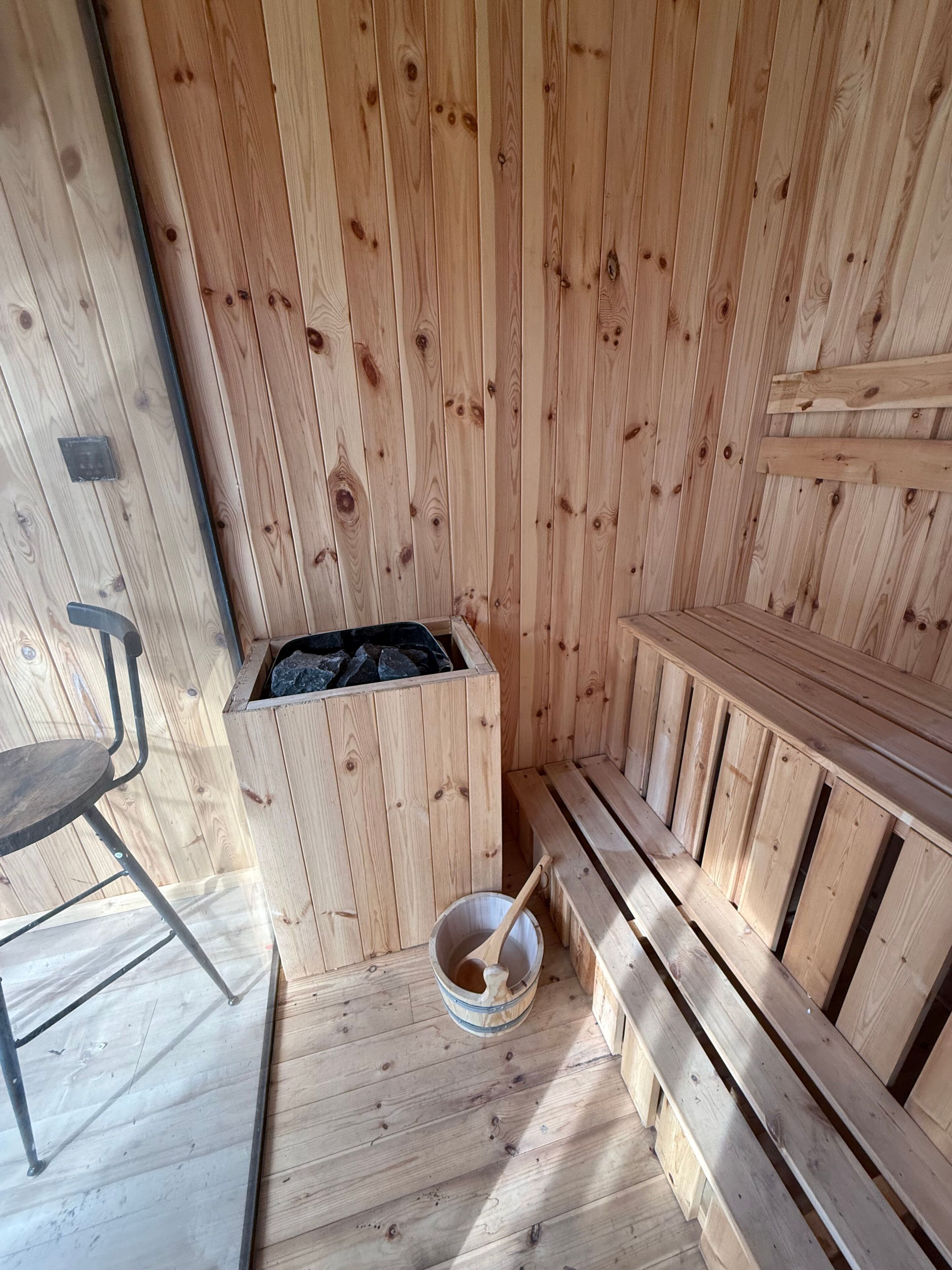 Eine Holzsauna mit Bänken und einem Eimer.