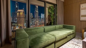 Ein modernes Wohnzimmer mit einem grünen Sofa, großen Fenstern und Blick auf die Stadt sowie einer Holzwandverkleidung.