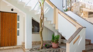 A staircase with stone steps and a wooden handrail, leading to a door with vertical blinds. - Apartment Luce 2 (Povljana)