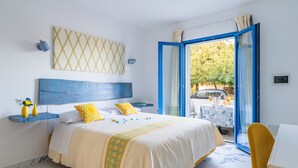 Un dormitorio con cama, mesita de noche, silla, mesa y vista al exterior.