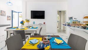 Un comedor moderno con televisor, armarios blancos y una barra desayunadora.