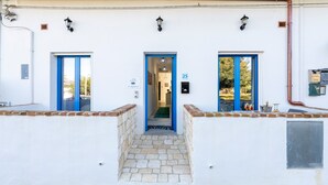 Un edificio con una escalera de piedra que lleva a una puerta azul con el número 25, fachada blanca y base de ladrillo.