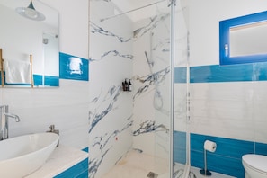 Une salle de bain avec un lavabo blanc, une cabine de douche en verre et des toilettes.