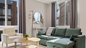 En moderne stue med en grøn sofa, en hvid lænestol og et rundt sofabord.