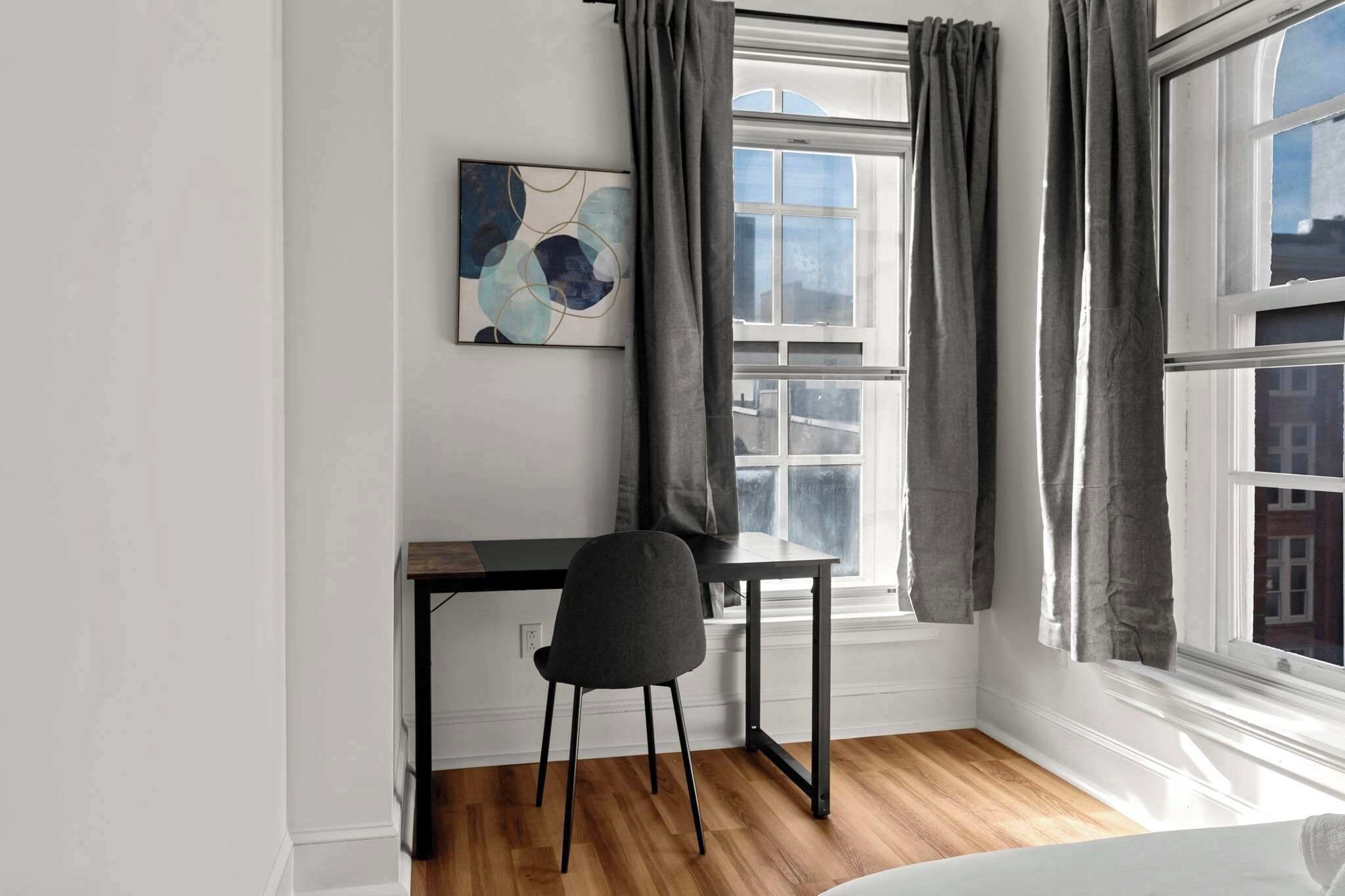 A room with a desk, chair, and a window with curtains.