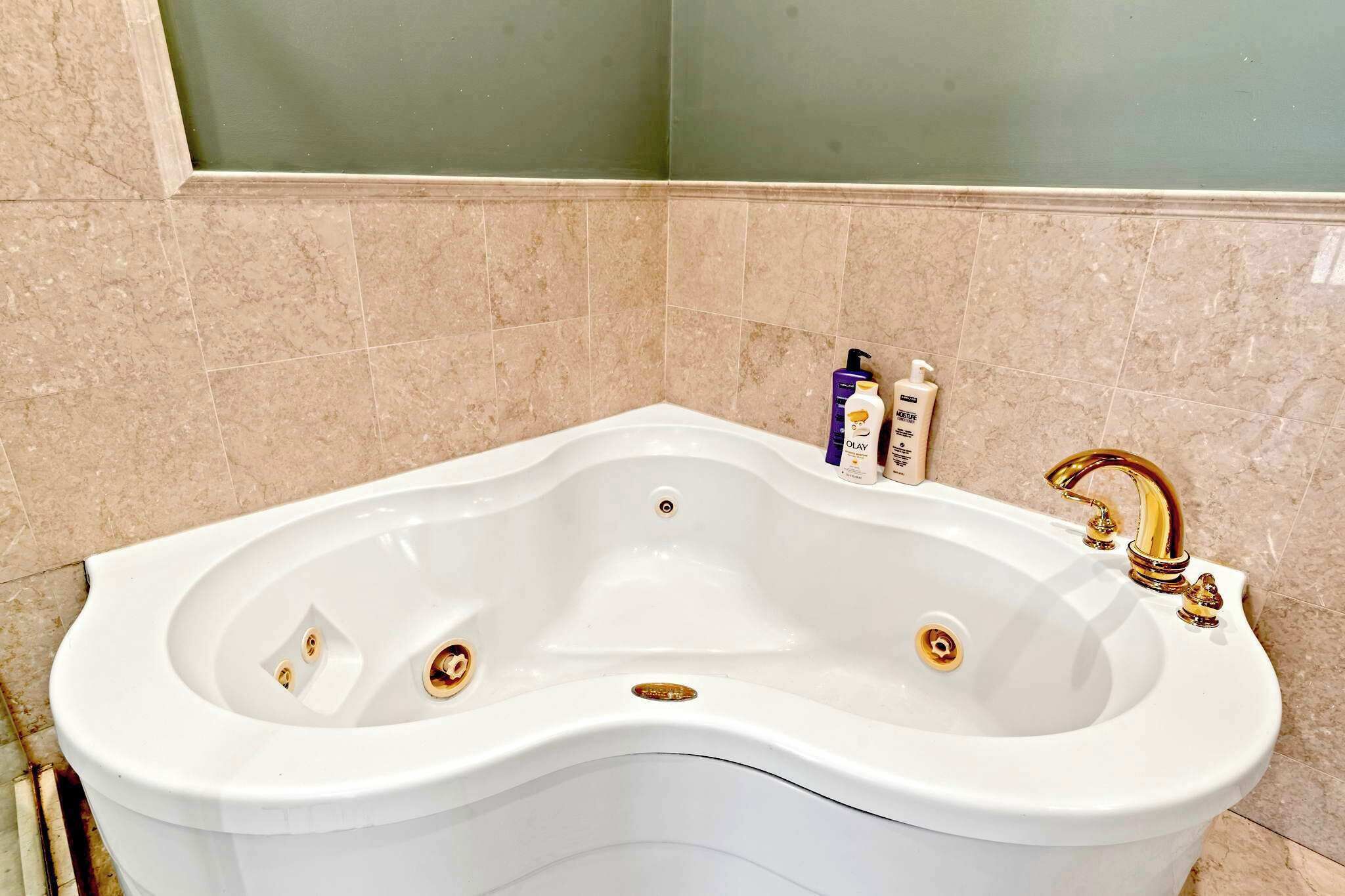 Eine freistehende, weiße Badewanne mit einem Wasserhahn und zwei Abflüssen.