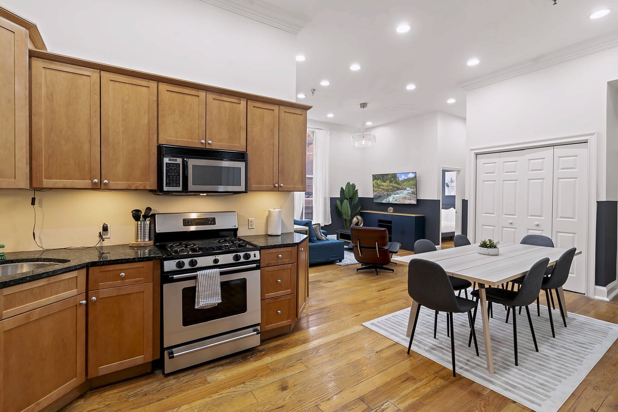 A modern kitchen with wooden cabinets, stainless steel appliances, and a dining area with a table and chairs.