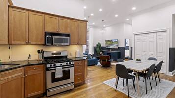 A modern kitchen with wooden cabinets, stainless steel appliances, and a dining area with a table and chairs.