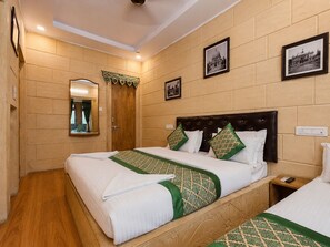 Une chambre d’hôtel avec deux lits, une tête de lit en bois, un miroir et des tableaux encadrés accrochés au mur.