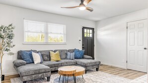 Ein modernes Wohnzimmer mit Ecksofa, rundem Couchtisch und Deckenventilator.