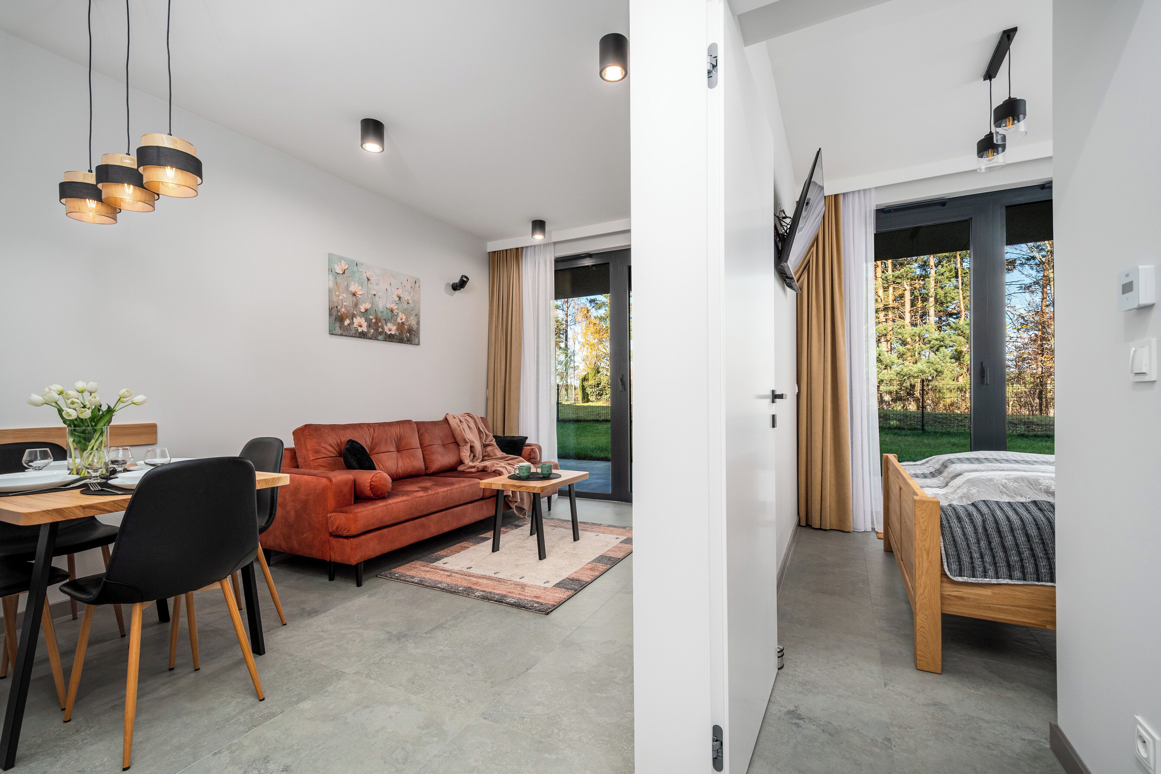 A modern living room with a dining area, a sofa, and a bed.