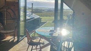 A spacious attic room with a large skylight, wooden beams, a hanging chair, and a table with chairs. - Exclusive Couples retreat surrounded by beautiful North Devon countryside. (Burrington)
